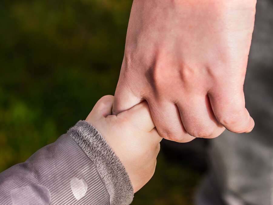 Ребенка держит за руку